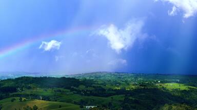 Impressive view at the tropical tableland with a colourful rainbow during rainseason.A heavy tropical rain falling down on the forests and valleys. Millaa Millaa Lookout,Far North Queensland,Australia