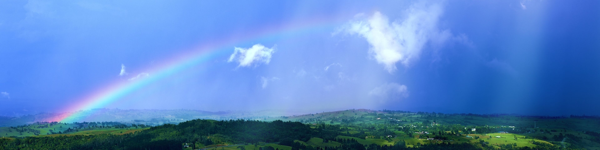 Impressive view at the tropical tableland with a colourful rainbow during rainseason.A heavy tropical rain falling down on the forests and valleys. Millaa Millaa Lookout,Far North Queensland,Australia