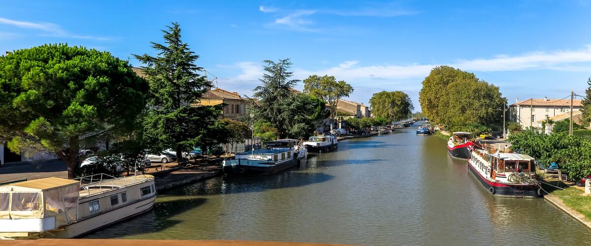A canal with boats, trees, and buildings along the banks.