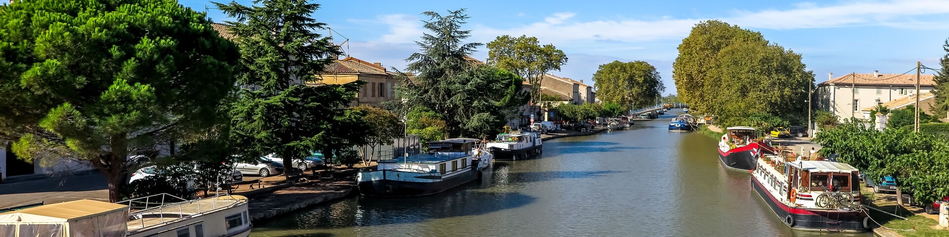 A canal with boats, trees, and buildings along the banks.