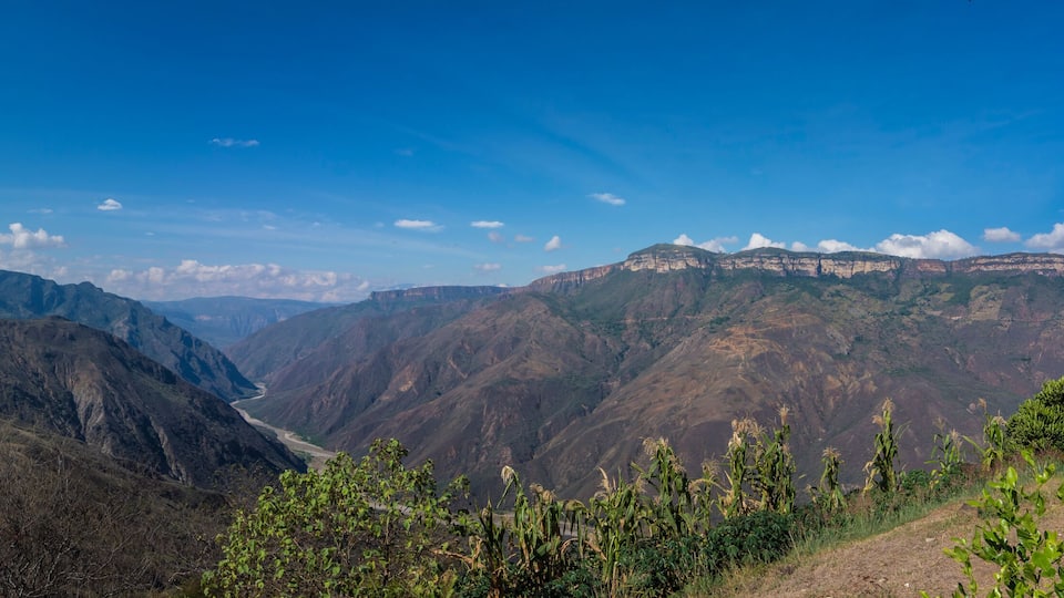A mountainous landscape with a valley and distant cliffs.