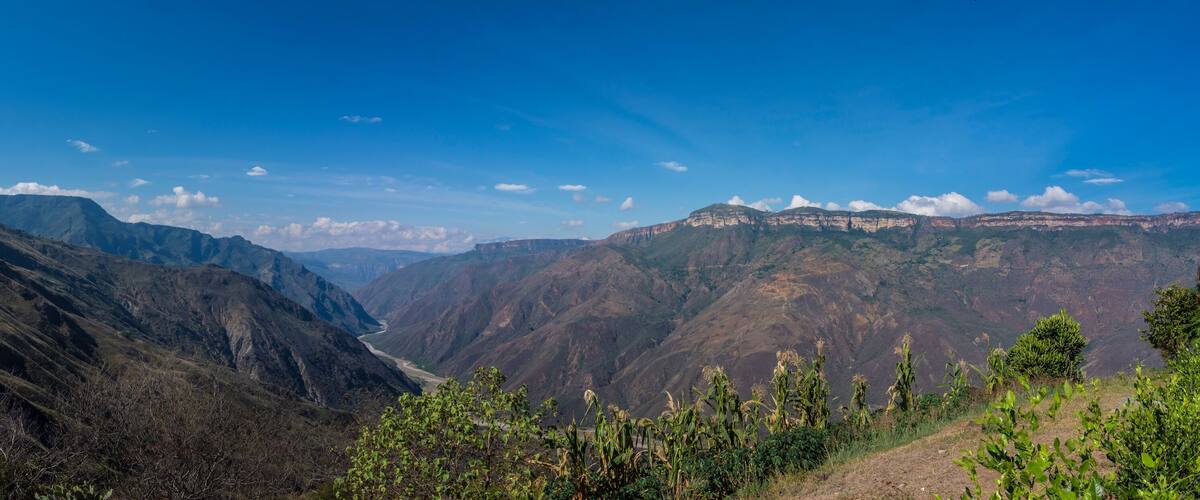 A mountainous landscape with a valley and distant cliffs.