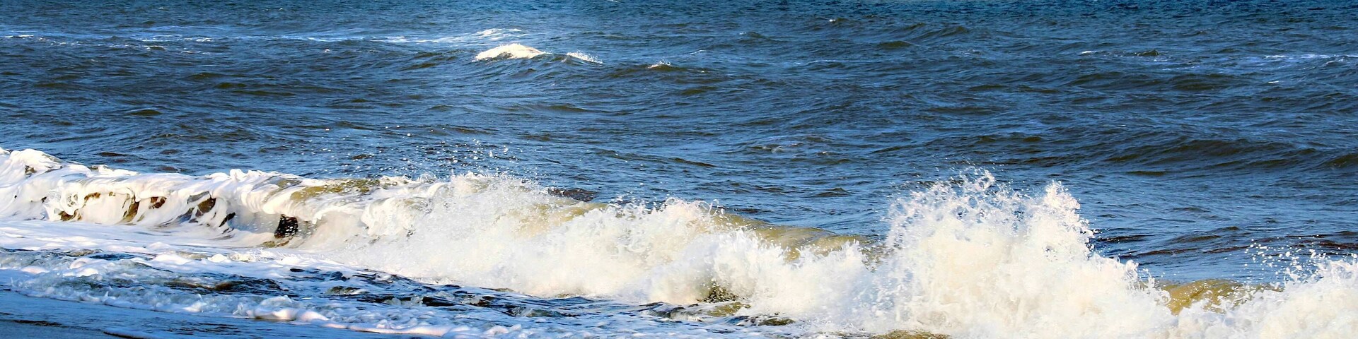 Una playa con olas rompiendo en la orilla bajo un cielo nublado.