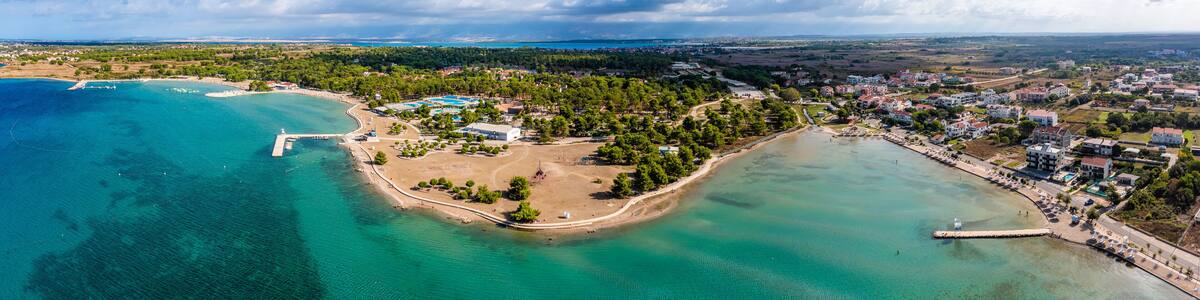 Zaton, Croatia - Aerial wide panoramic view of Zaton tourist waterfront with turquoise sea water, Nin village and Velebit mountains at background on a sunny summer day in Dalmatia region of Croatia