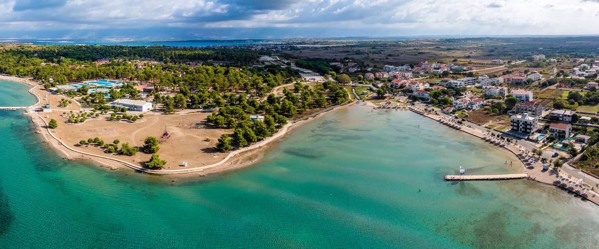 Zaton, Croatia - Aerial wide panoramic view of Zaton tourist waterfront with turquoise sea water, Nin village and Velebit mountains at background on a sunny summer day in Dalmatia region of Croatia