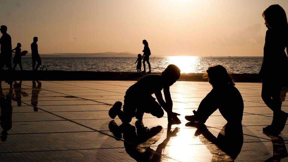 Silhouettes of people at a waterfront during sunset.