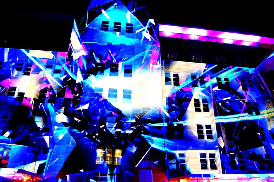 A building with a complex, geometric facade and bright, colorful lighting.