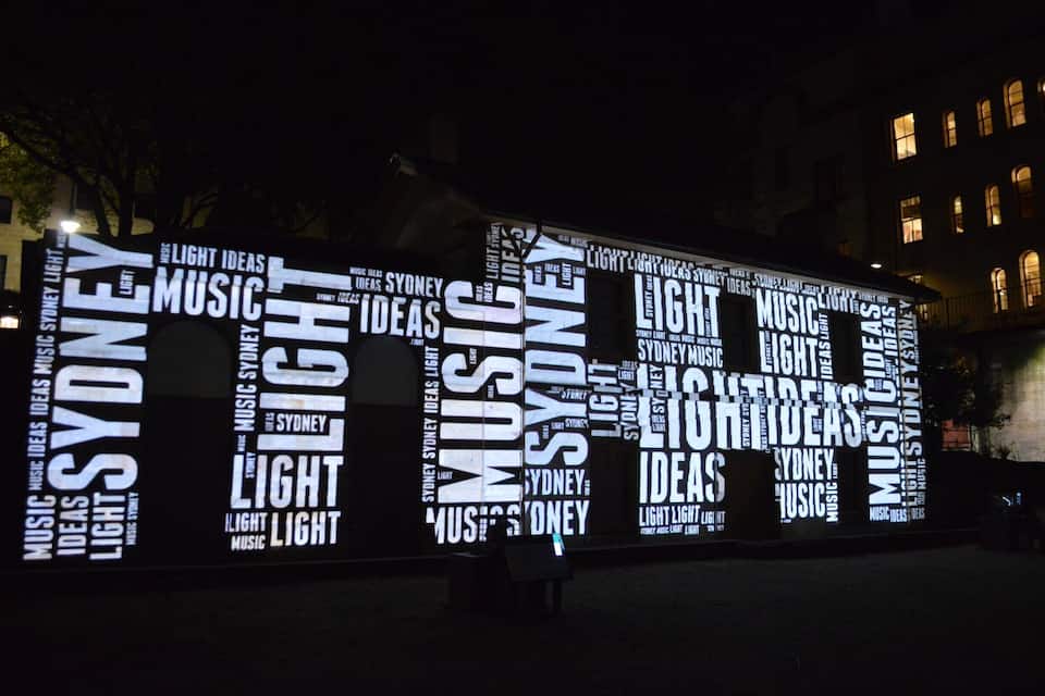 A large illuminated sign with repeated words 'SYDNEY,' 'LIGHT,' 'MUSIC,' and 'IDEAS.'
