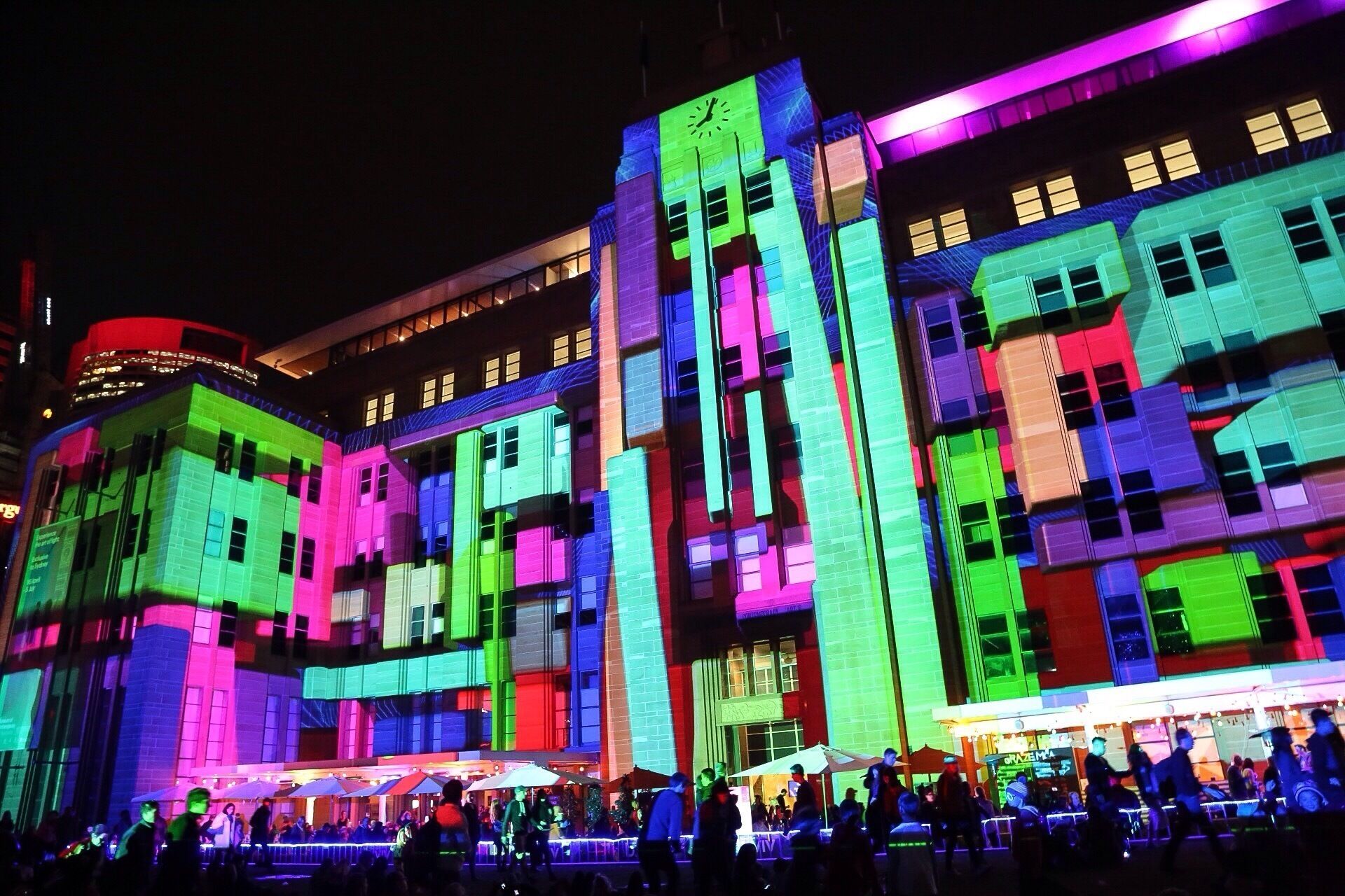 A brightly lit building with colorful lights and a clock tower.