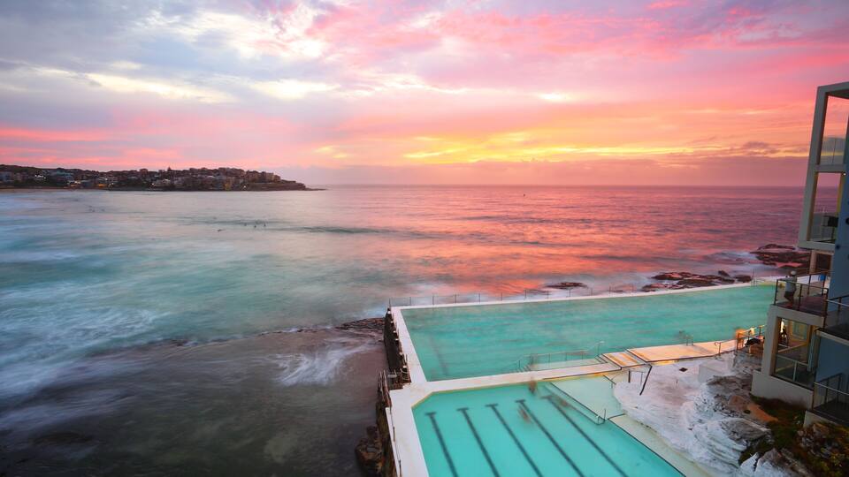 Un atardecer costero con una piscina y edificios.