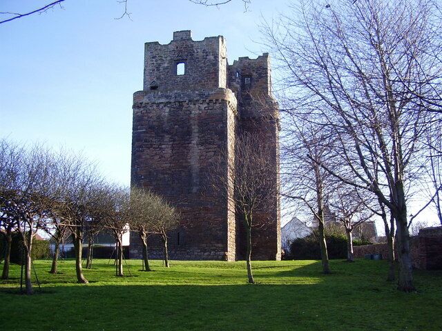 A historic stone tower with battlements, surrounded by a grassy area with leafless trees.