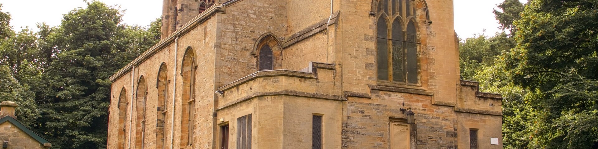Uma igreja de pedra histórica com uma torre imponente e janelas em arco.