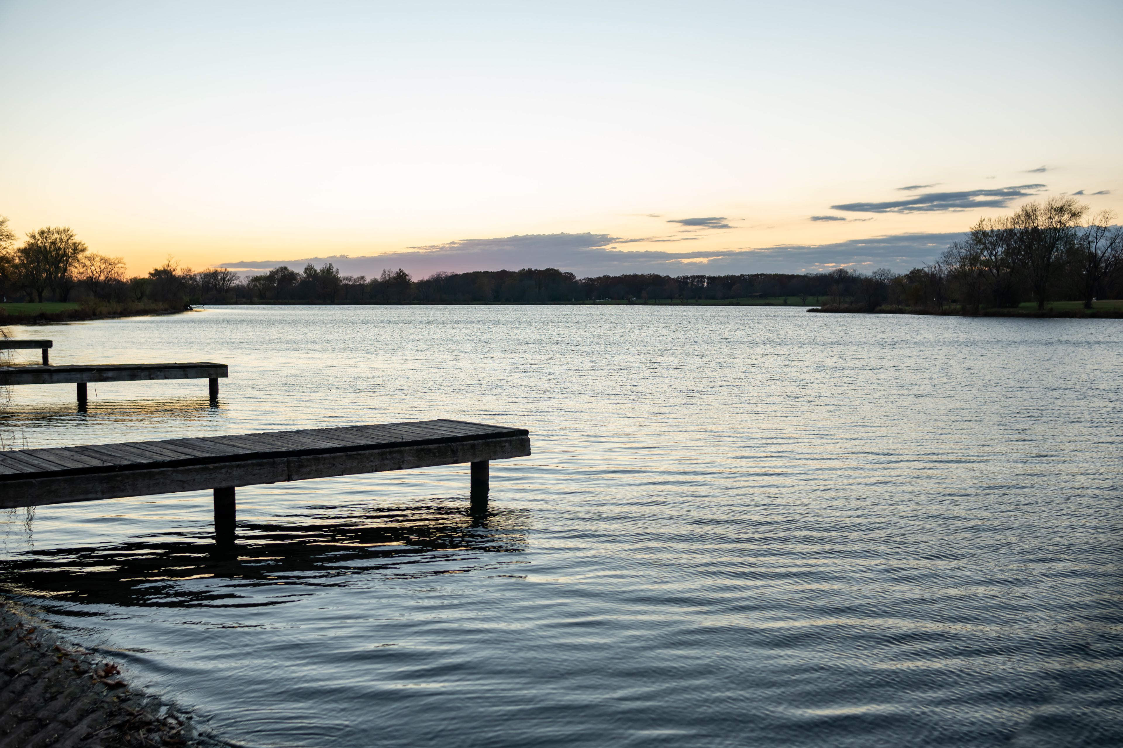A calm lake with a wooden dock extending into the water.