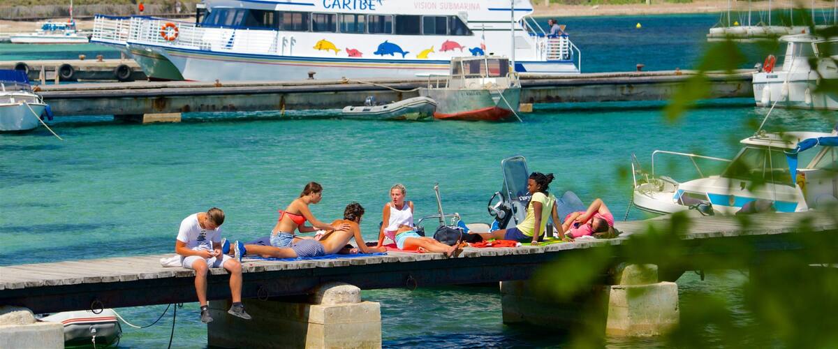 A ferry named "CARIBE" docked at a pier with people relaxing on the dock.
