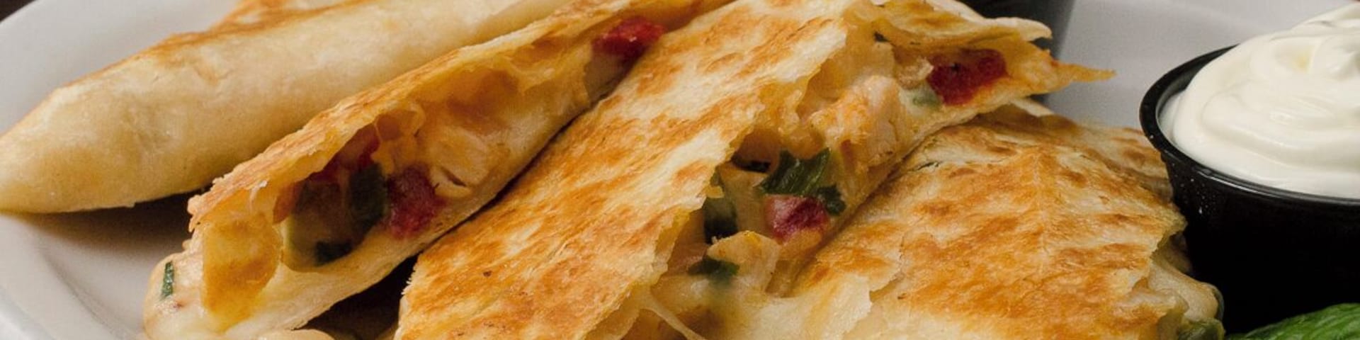 The Grilled Chicken Quesadilla from The Irish Legend Pub and #Restaurant, made with roasted chicken, chiuahua cheese, onions, and red bell pepper, served with a side of sour cream.