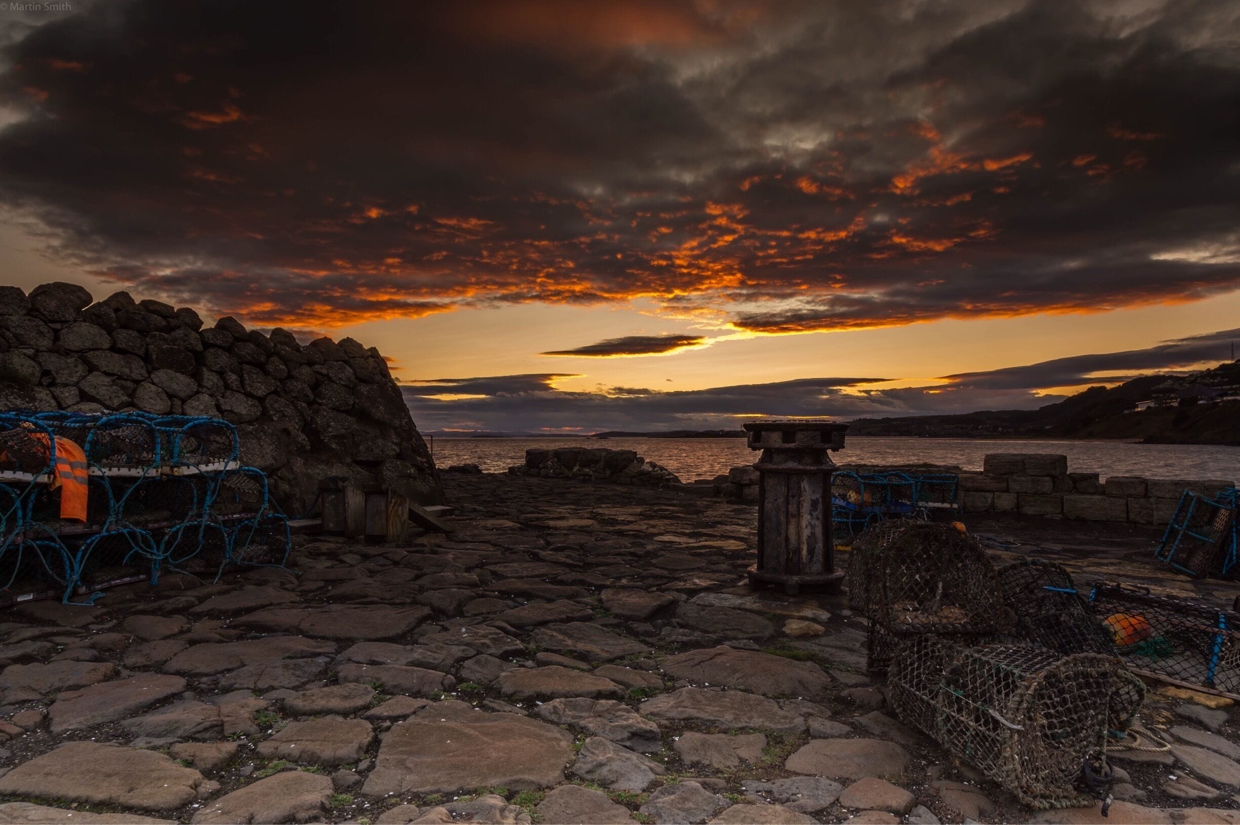 A rocky shoreline with fishing traps and a stone wall.