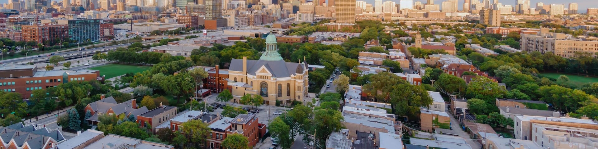 A cityscape with a prominent skyscraper, dense urban buildings, and a green park area.