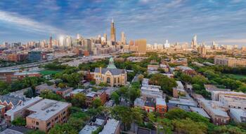 Un paisaje urbano con un rascacielos destacado, edificios urbanos densos y una zona verde de parque.