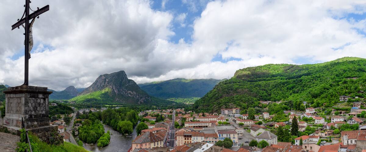 A town with a river, a mountain, and a cross monument.