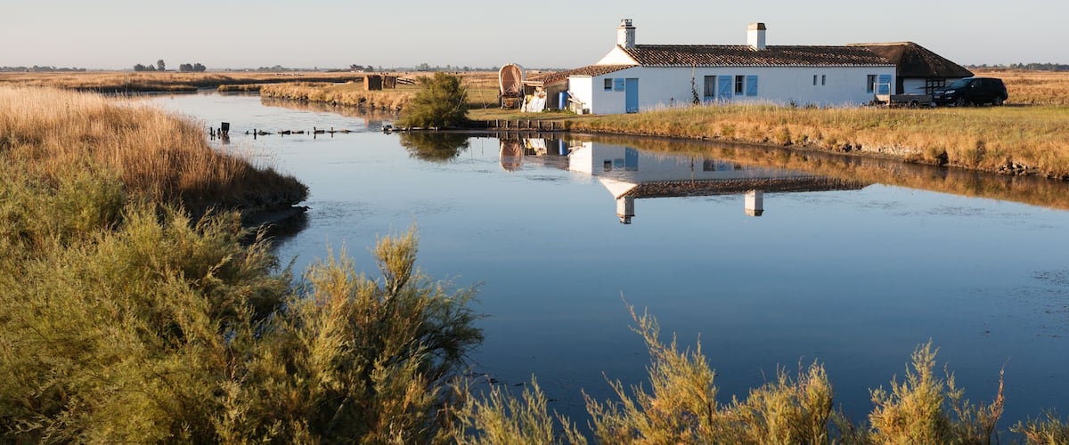 A calm river with a house and a car on the right bank.