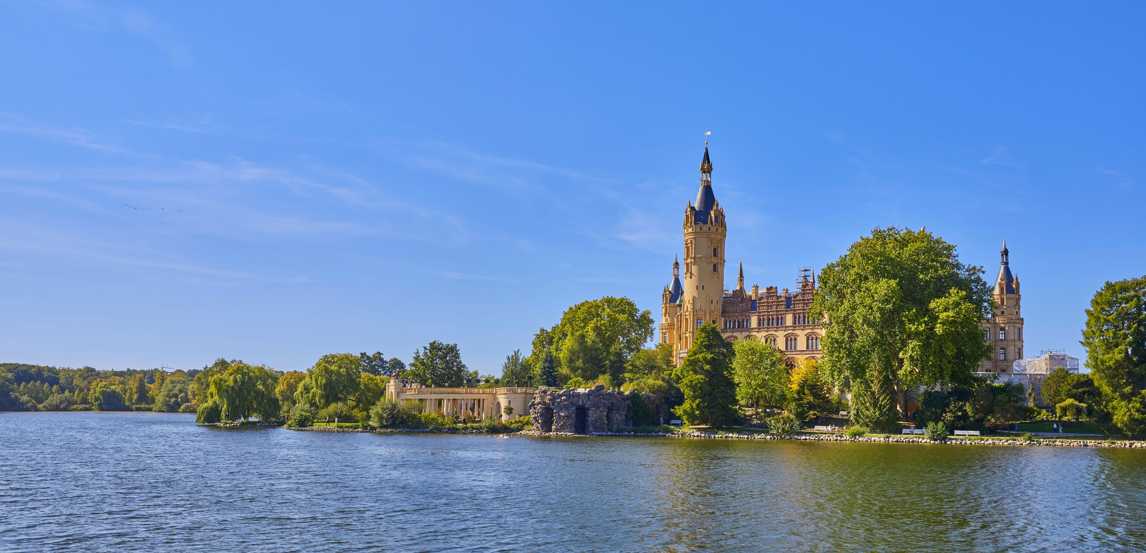 A castle by a lake with a prominent tower and a bridge.