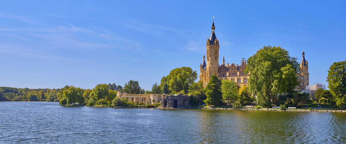 A castle by a lake with a prominent tower and a bridge.