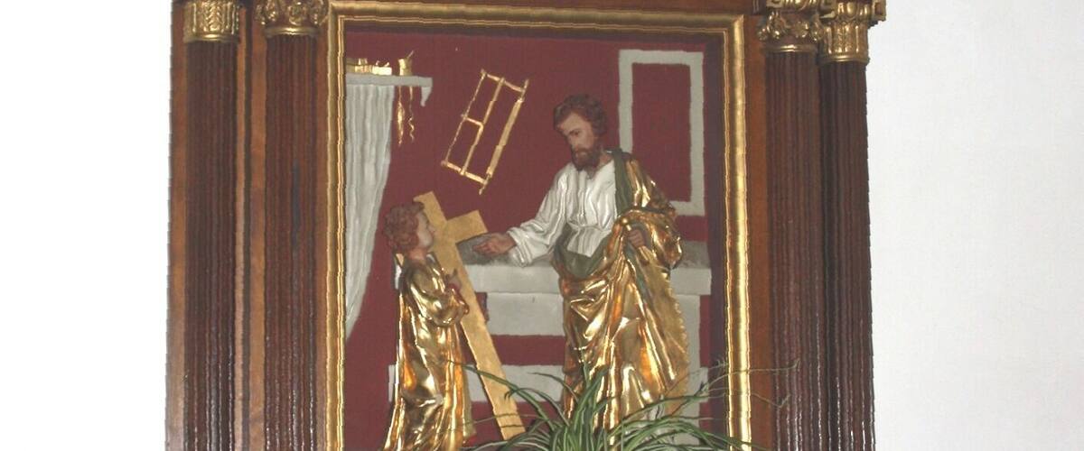 A wooden religious icon with gold accents and a cross on top.