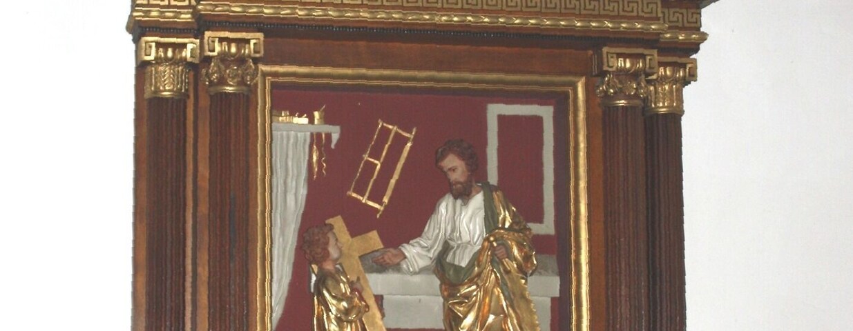A wooden religious icon with gold accents and a cross on top.