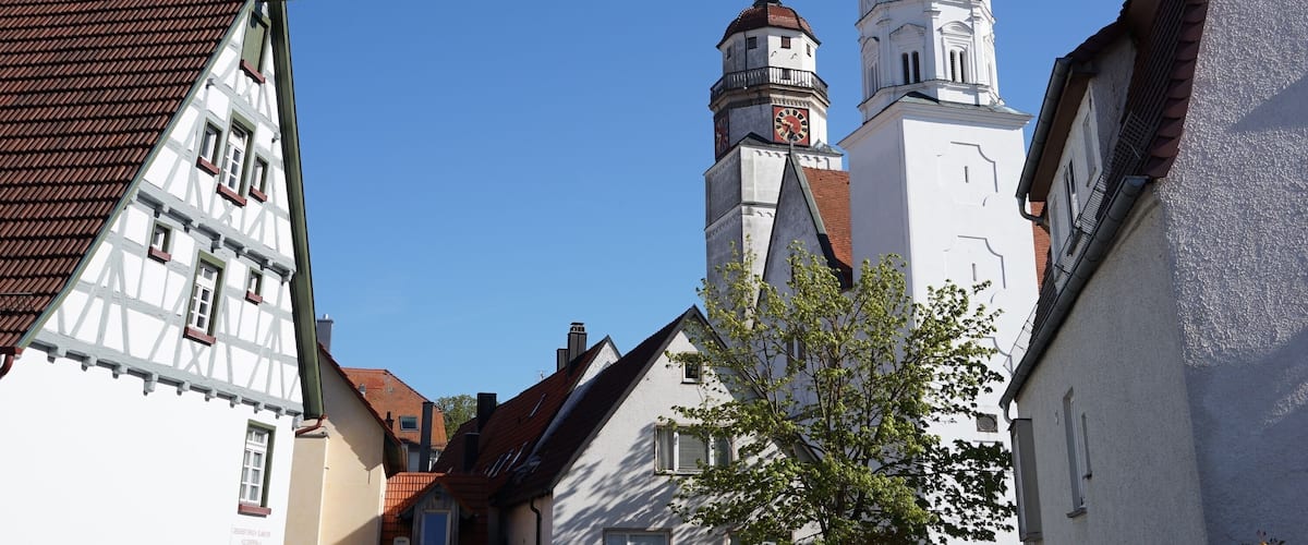 A church with a clock tower and a steeple under a clear blue sky.