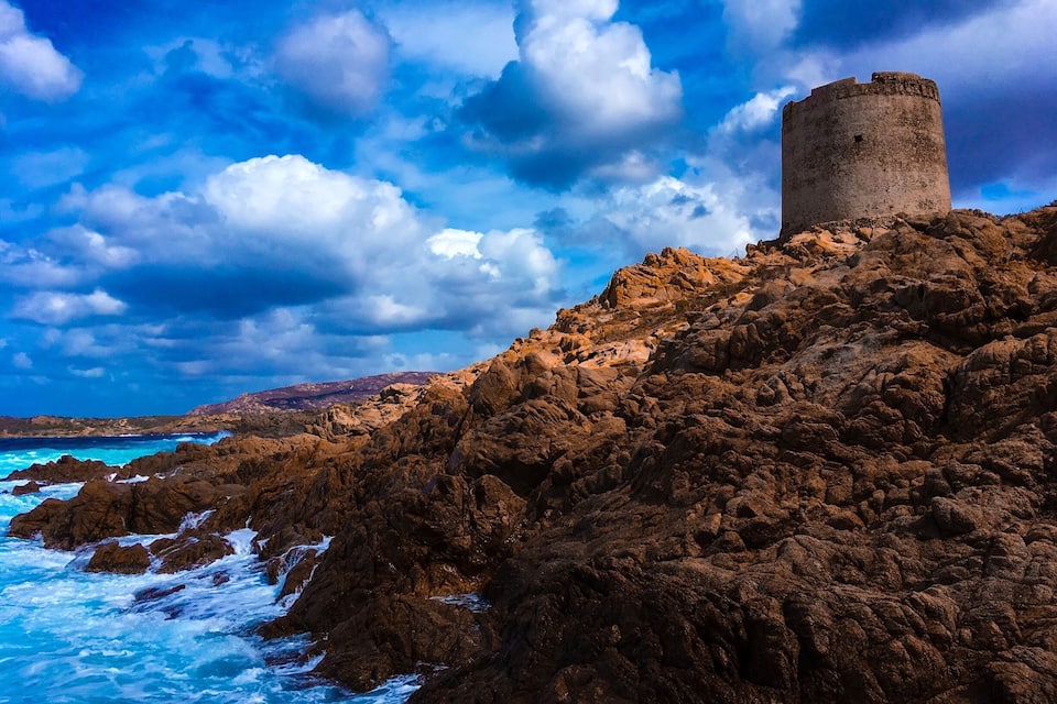 A rocky coastline with a historic stone tower.