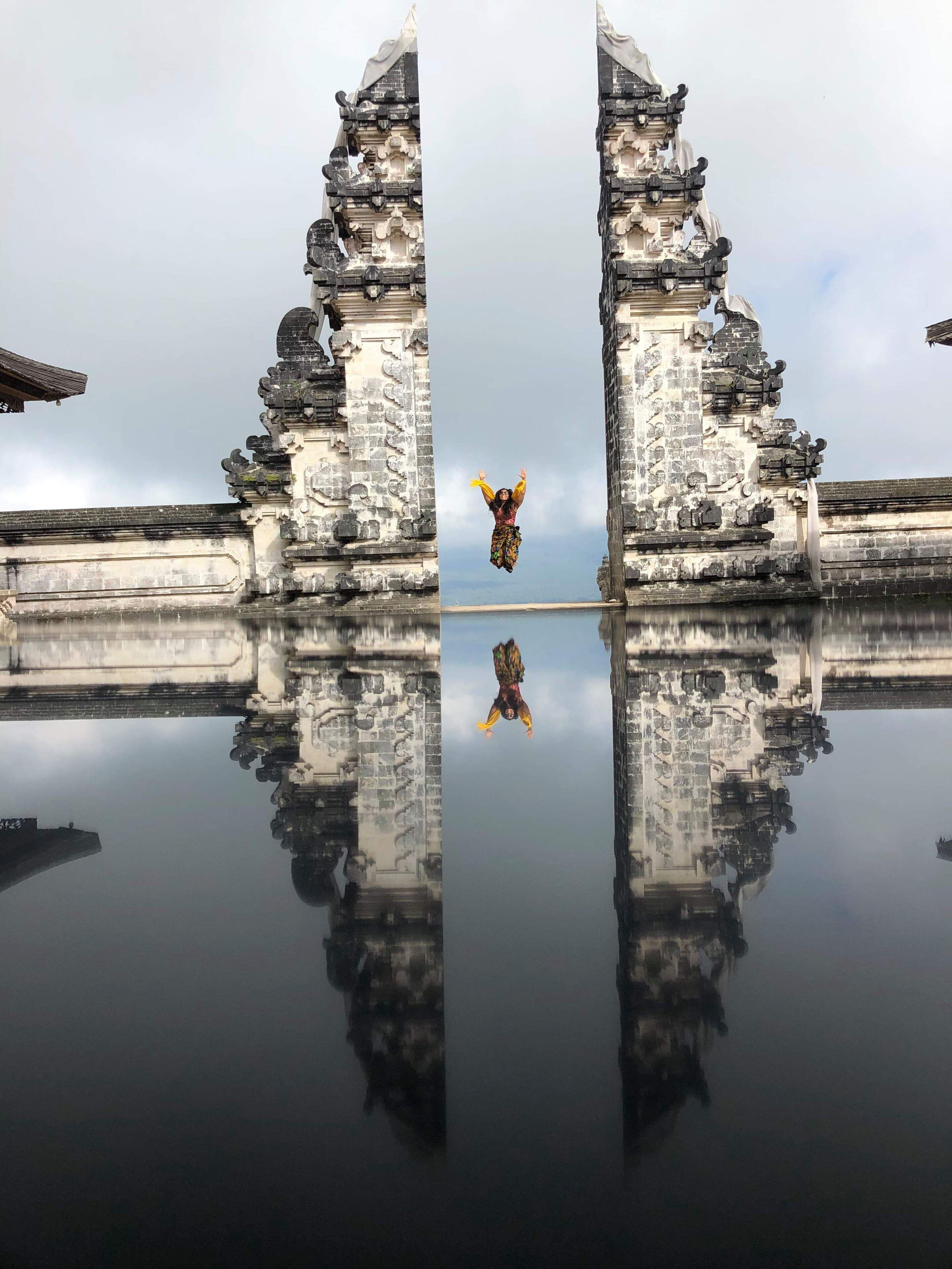 A temple with intricate carvings and a person jumping in the center.