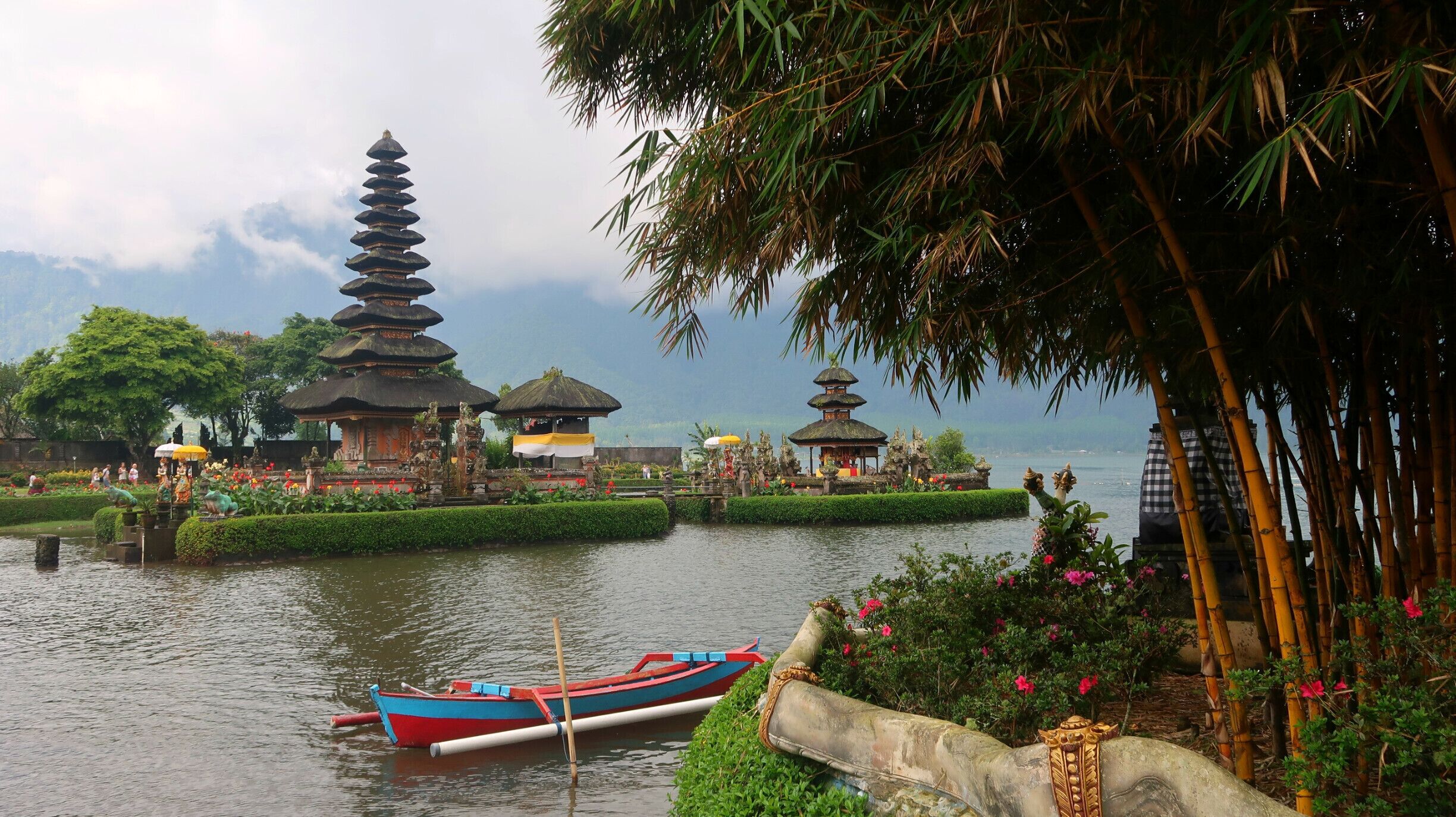 A traditional temple with tiered roofs, a lotus pond, and a small boat.