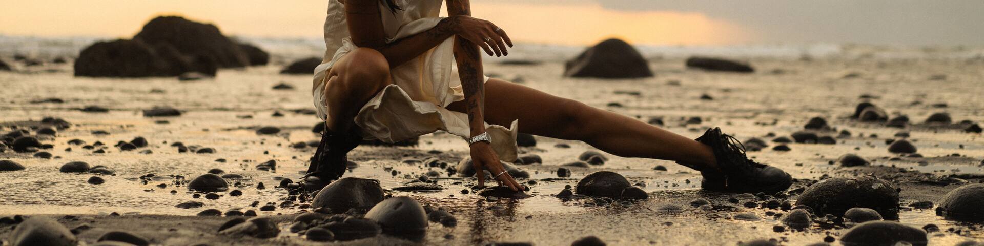A person sitting on a rocky beach with the ocean in the background.