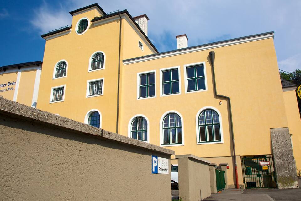 Ein gelbes Gebäude mit zahlreichen Fenstern und einem Schild, das Fahrradstellplätze kennzeichnet.