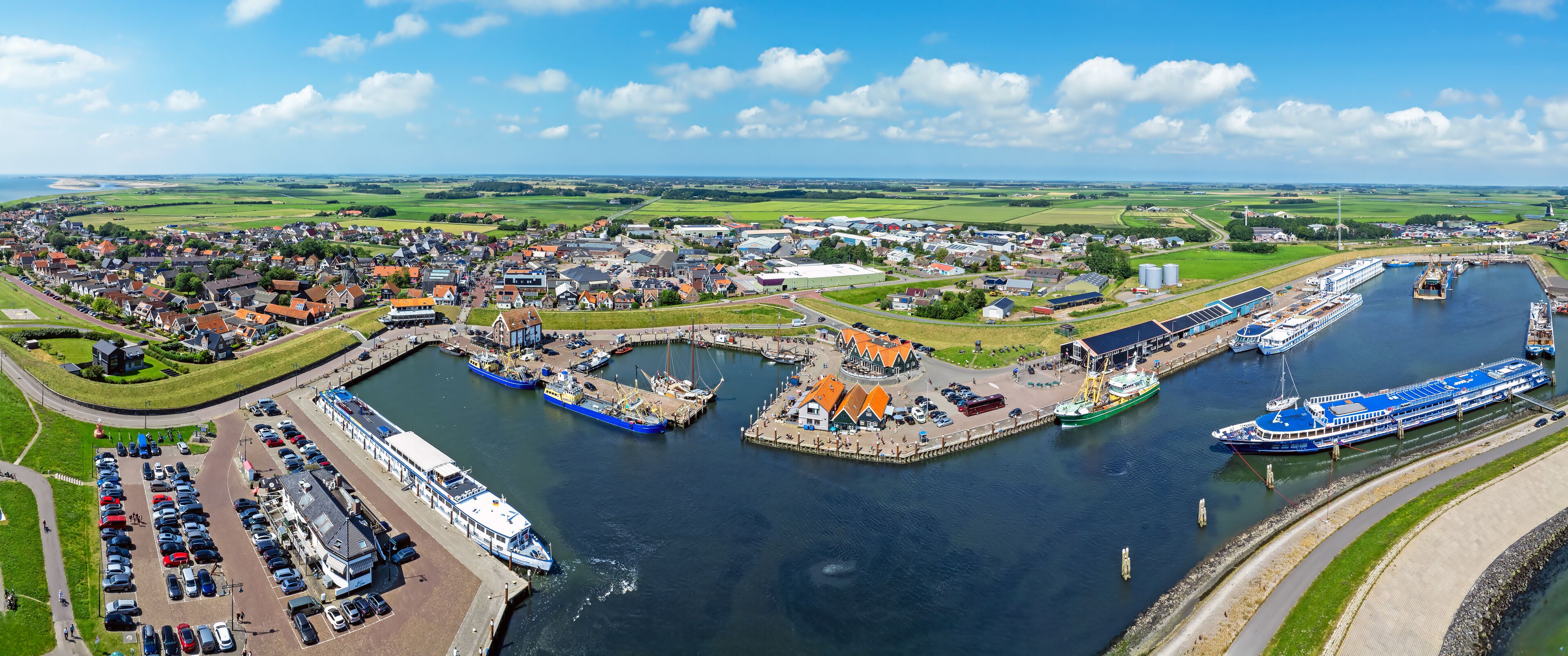 A coastal town with a marina, boats, and a large ship docked at the pier.