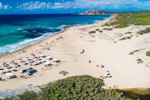 Une plage avec des tentes, des parasols et des gens.