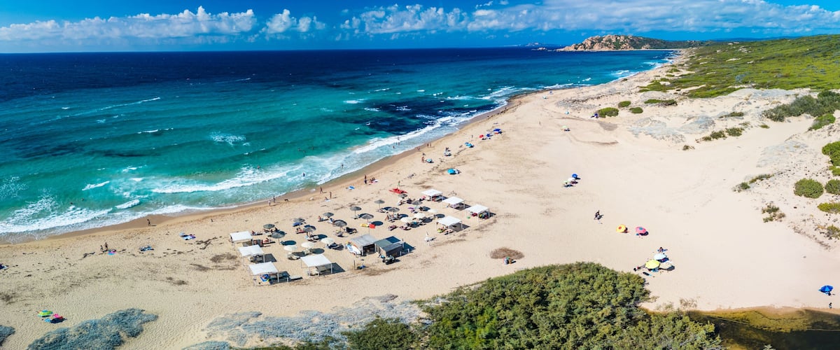 A beach with tents, umbrellas, and people.