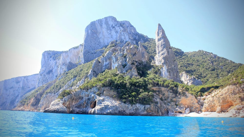 Eine Küstenlandschaft mit einem markanten Felsen und blauem, klarem Meer.