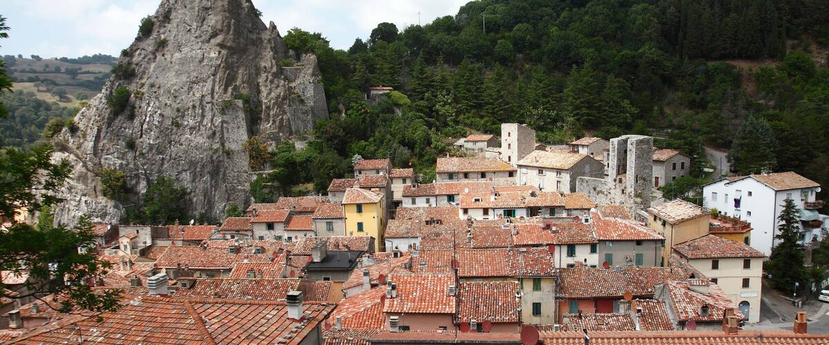 A town with terracotta-roofed buildings nestled against a rocky cliff.