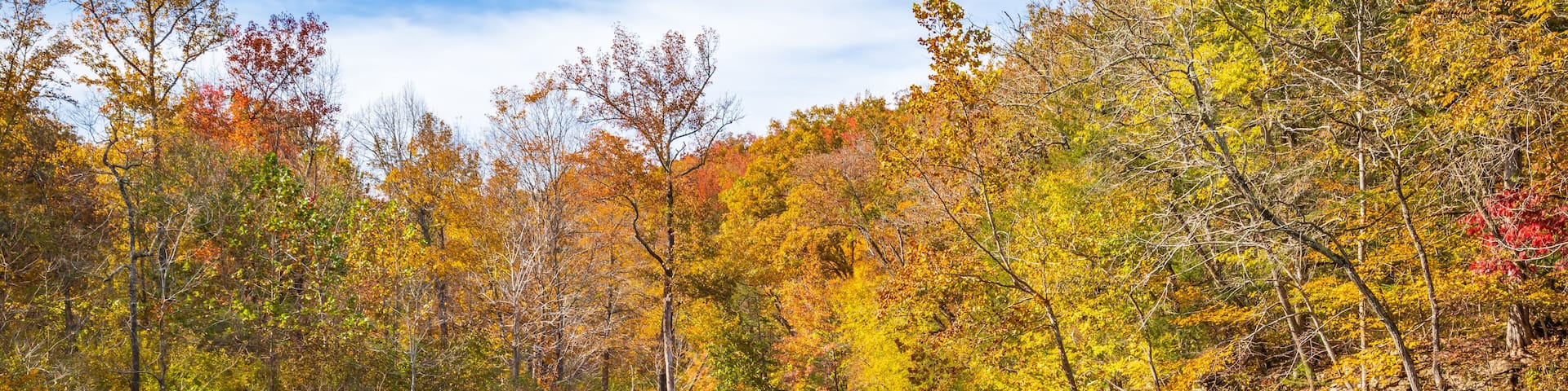 A clear lake surrounded by autumn-colored trees and rocky cliffs.