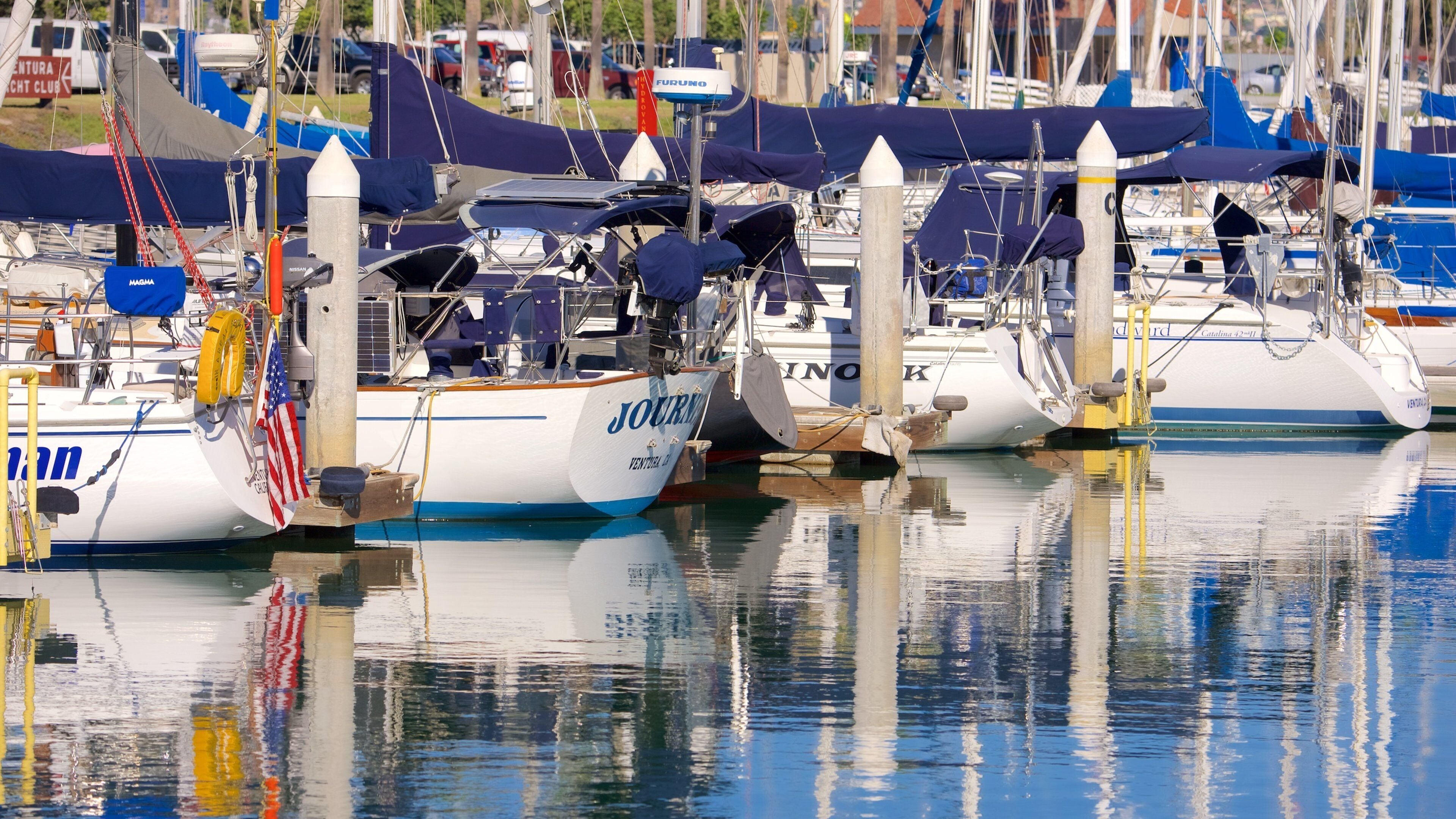 Un port de plaisance où plusieurs bateaux sont amarrés, dont un qui s’appelle « JOURNAL ».