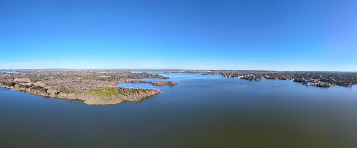 A coastal landscape with a large body of water, several small islands, and a distant city skyline.