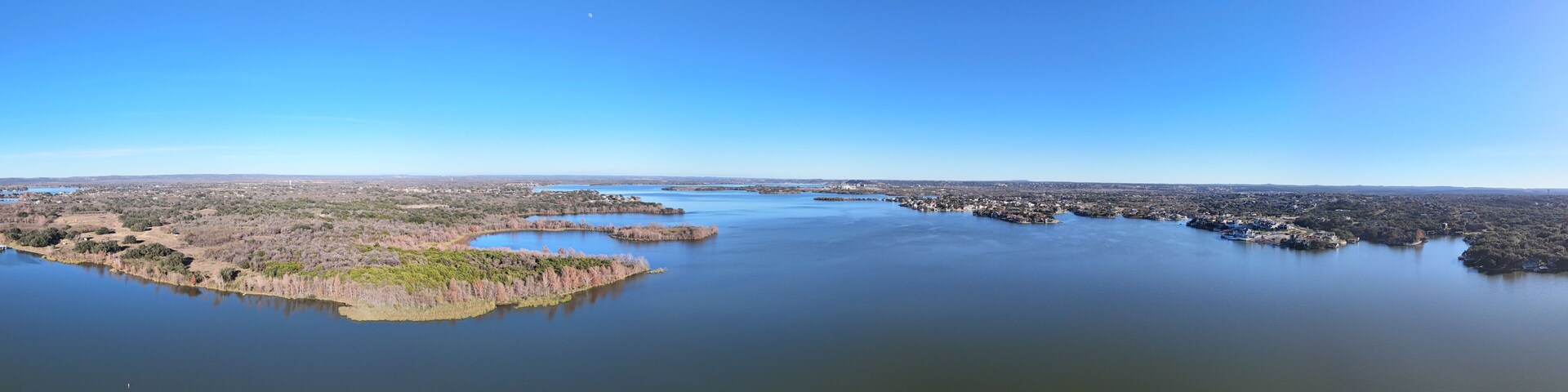 A coastal landscape with a large body of water, several small islands, and a distant city skyline.