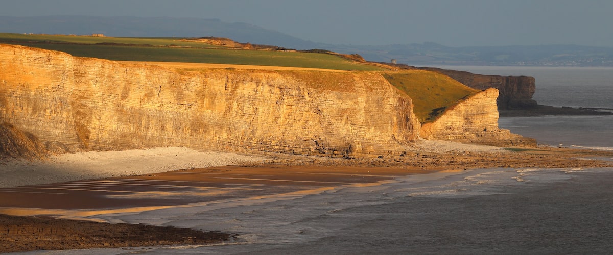 A coastal landscape with cliffs and a beach.