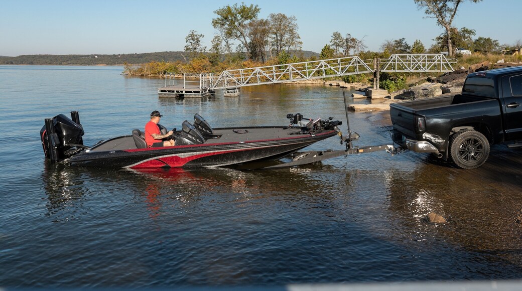 man launching bass boat at a sunny lakeside ramp