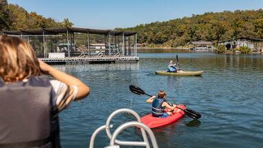 boy watching brother and dad kayak on lake