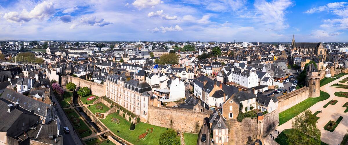A historic cityscape with a prominent castle, narrow streets, and a mix of traditional and modern architecture.