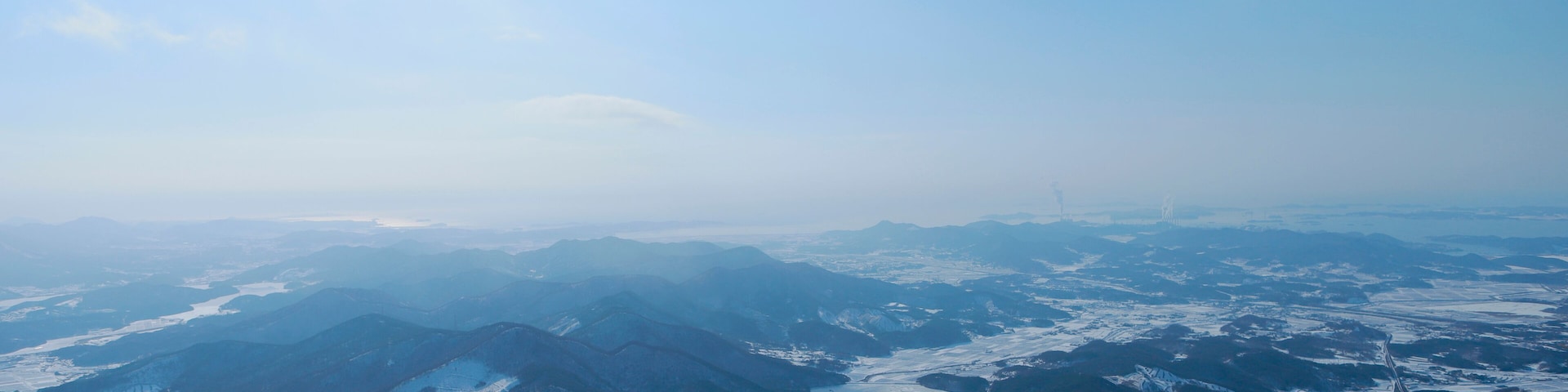 A panoramic view of snow-covered mountains and valleys under a clear sky.