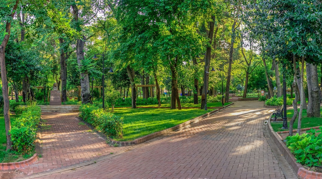 A park with a paved walkway, lush greenery, and a sign indicating a distance of 100m.