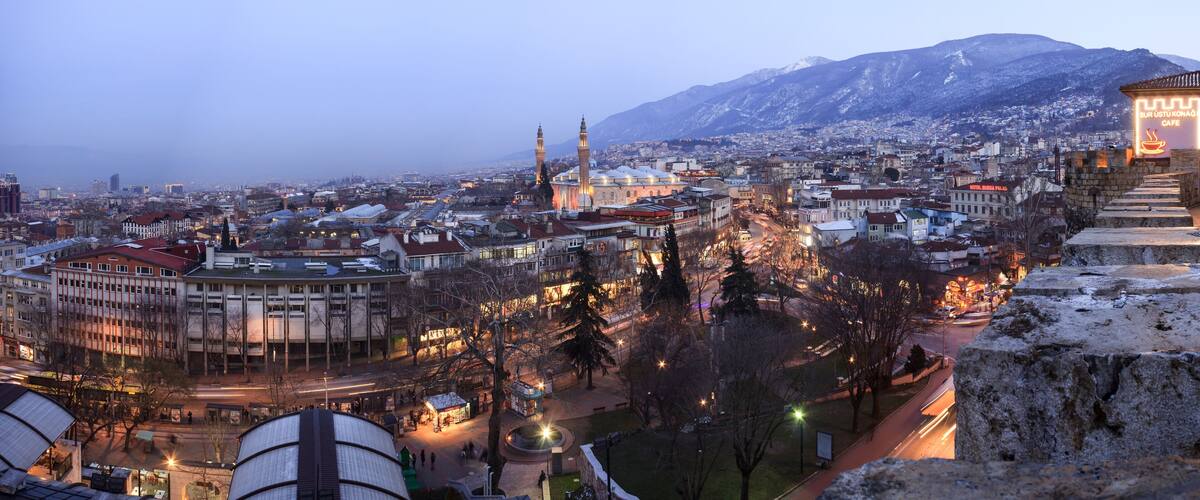 A cityscape with a prominent mosque, snow-covered buildings, and a mountain in the background.